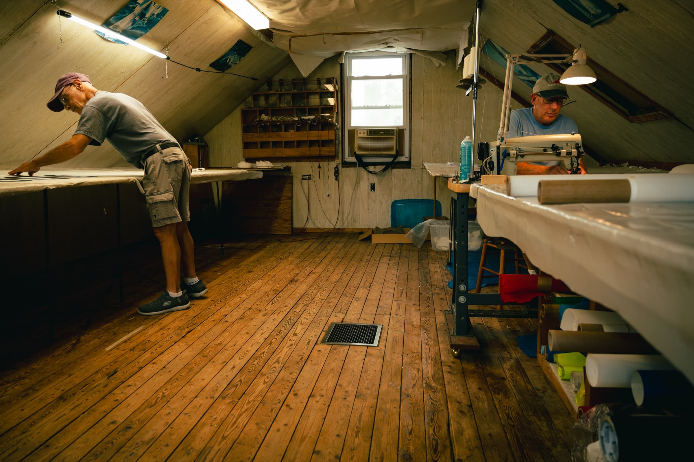 Inside the Rogers' Sail Loft attic: one craftsman at a cutting table, another at a sewing machine
